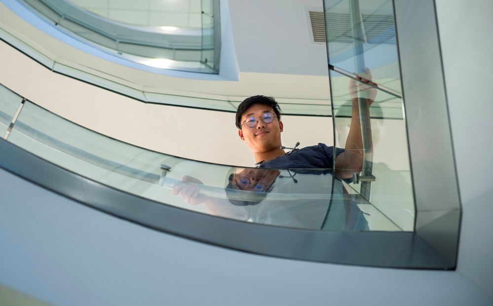 A low angle shot of an Asian-American male student in a stairwell smiling